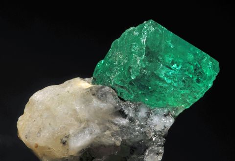 Cristal d'émeraude brute sur sa roche, sur fond noir